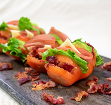 Hassleback tomatoes with shalow slices through them have the slices stuffed with Halal beef bacon, lettuce, halal chicken bologna, avocado, and cheese. 