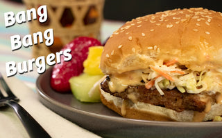 A Halal burger on sesame bun with coleslaw and bang bang sauce on top.  