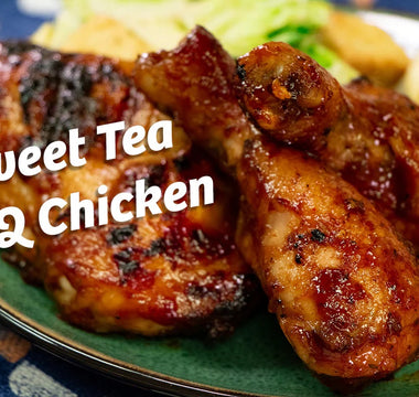 A Halal chicken drumstick leans on a larger chicken thigh both are glazed with bbq sauce. 