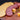 Halal beef summer sausage in slices fanned out in a curve, butter crackers are fanned out to the left of them, a cube of colby jack cheese is to the right and some pistachios are scattered around.